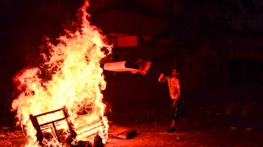 A left-wing protester throws wood into a fire lit by protesters, to help avoid tear gas used by police to disperse them, in Istanbul, Sunday, July 26, 2015. (AP)