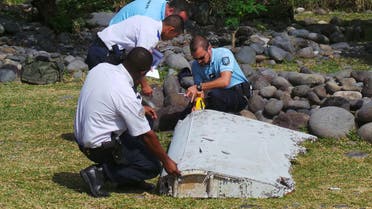 French gendarmes and police inspect a large piece of plane debris which was found on the beach in Saint-Andre, on the French Indian Ocean island of La Reunion, in this picture taken July 29, 2015. Investigators in France have ascertained that the barnacle-covered debris, a 2-2.5 metre (6.5-8 feet) wing surface known as a flaperon, belonged to Malaysia Airlines flight MH370 just days after Malaysia identified it as being part of the same model, a Boeing 777. Picture taken July 29, 2015. REUTERS/Zinfos974/Prisca Bigot/Files