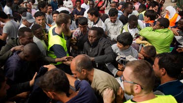 Migrants scuffle for clothes distributed by a local NGO at a camp set near Calais, northern France, Sunday, Aug. 9, 2015. An estimated 2,500 migrants are currently at the windswept camp surrounded by sand dunes that sprung up when a state-approved day center for migrants was opened nearby. The ramshackle encampment of tents and lean-tos is referred to as the "jungle," like the camps it replaced. (AP Photo/Emilio Morenatti)