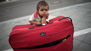 Migrant boy waits at his parents' suitcase as they leave the Berlin State Office for Health and Social Affairs with other newly arrived refugees who waited all day to apply for asylum in Berlin. (Reuters)