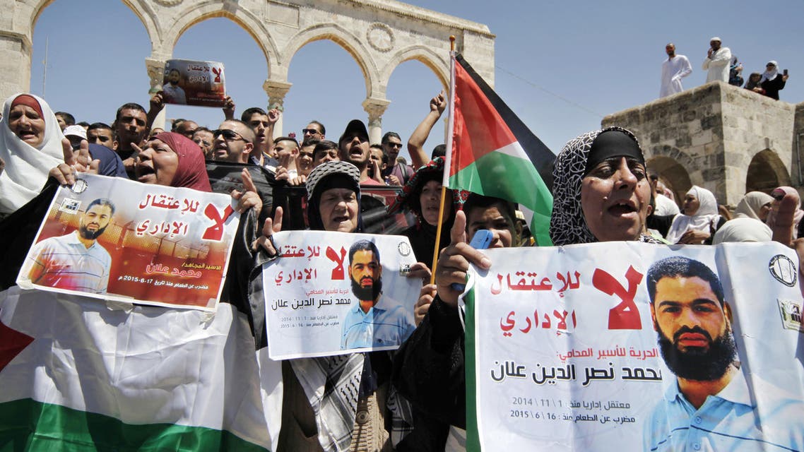 Protestors hold up Palestinian flags and posters with pictures of Palestinian detainee Mohammed Allan and Arabic that reads "no to the administrative detention, freedom for the lawyer prisoner, detained November 1, 2014," during a protest near the Dome of the Rock Mosque, in the Al Aqsa Mosque complex, in Jerusalem's old city, Friday, Aug. 14, 2015. Mohammed Allan who has been on a hunger strike for 60 days slipped into unconsciousness on Friday and was being treated in the intensive care unit at an Israeli hospital. (AP Photo/Mahmoud Illean)