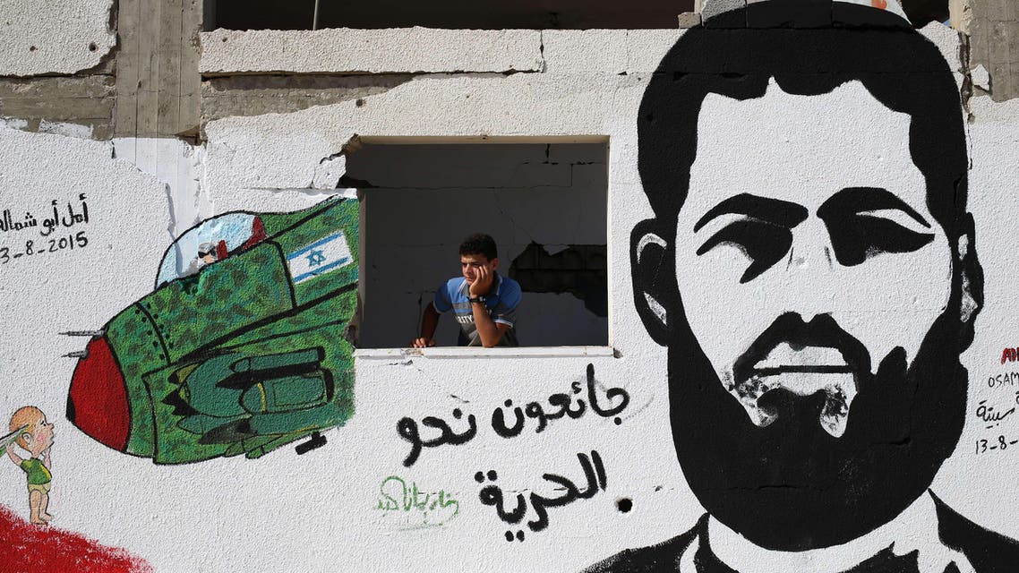 A Palestinian youth stands behind a wall sprayed with a graffiti depicting 31-year-old Mohammed Allan, Palestinian held by Israel without trial and who has reportedly slipped into a coma after a nearly two-month hunger strike, on August 16, 2015, in Gaza City. Allan, an alleged Islamic Jihad activist who has been held without charge by Israel since November, has been on hunger strike since June 18, according to the Palestinian Prisoners Club. AFP PHOTO / MOHAMMED ABED