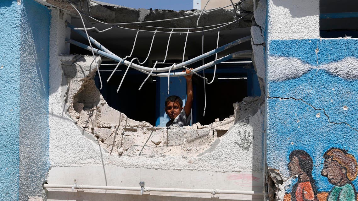 A boy looks through the wall of a building damaged by an Israeli strike at the Abu Hussein U.N. school in the Jebaliya refugee camp in the northern Gaza Strip on Wednesday, July 30, 2014. Israeli tank shells slammed into a crowded U.N. school Wednesday sheltering Gazans displaced by fighting, killing more than a dozen and wounding tens after tearing through the walls of two classrooms, a spokesman for a U.N. aid agency and a health official said. The Israeli military said mortar shells had been fired from near the school, and that soldiers fired back. (AP Photo/Hatem Moussa)