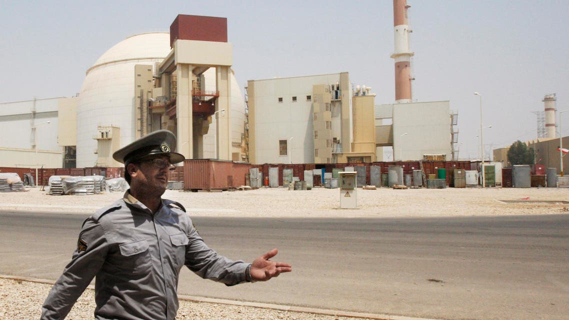 an Iranian security officer directs media at the Bushehr nuclear power plant, with the reactor building seen in the background, just outside the southern city of Bushehr, Iran.