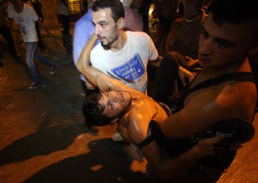 Lebanese demonstraters carry a man injured in clashes with security forces (AFP)