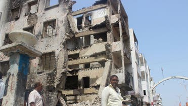 People walk past a building damaged by fighting recent between Houthi militants and fighters of the Southern Resistance, in Yemen's southern port city of Aden. (File photo: Reuters)