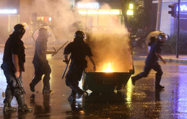 Lebanese security forces run towards a rubbish container set on fire by protesters (AFP)