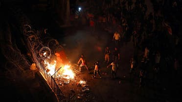 Lebanese activists set fire to plastic barriers and trash behind the barbed wire separating them from the police, during a protest against the ongoing trash crisis, in downtown Beirut. (AP)