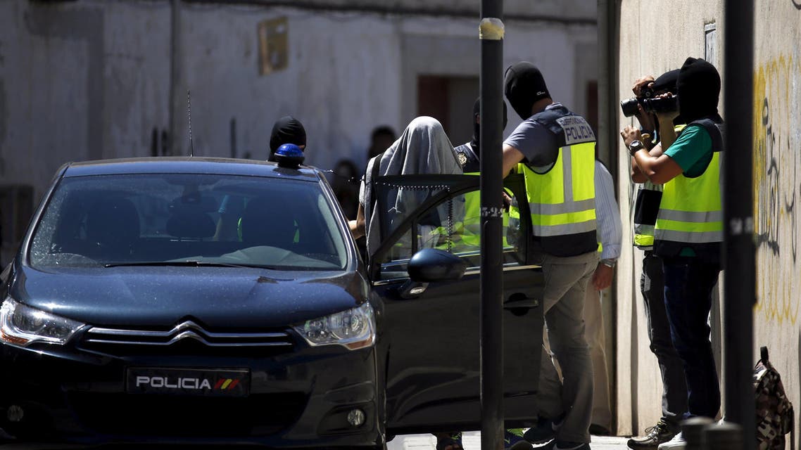 A suspect (L) is led by Spanish National Police officers after being arrested. (Reuters)