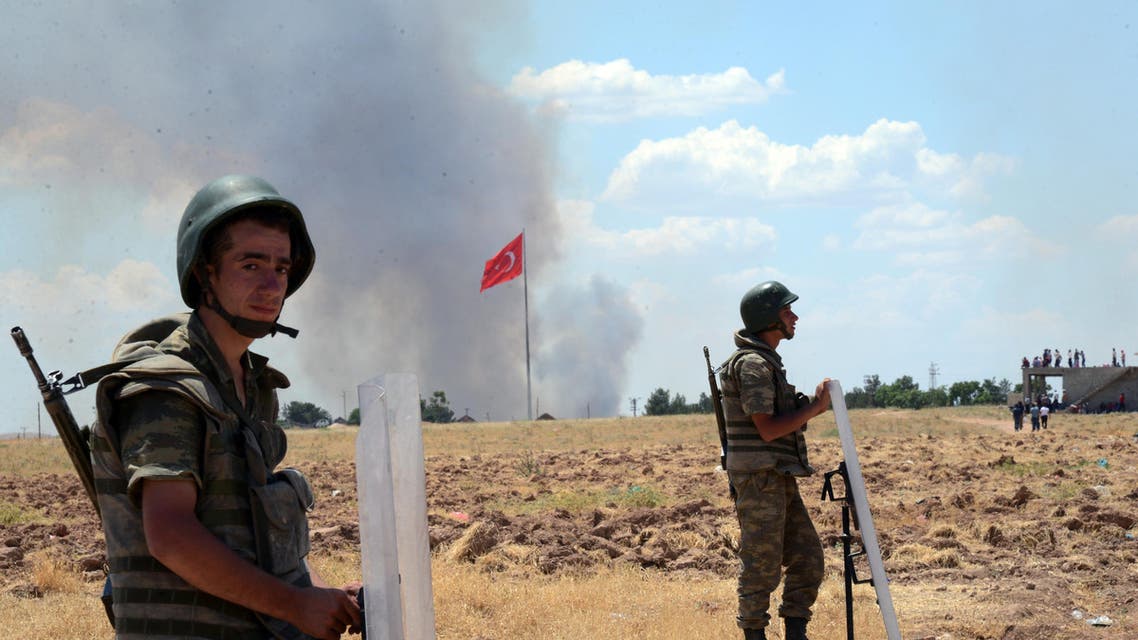 Turkish soldiers stand guard on the Turkish side of the border in Suruc, Turkey, Friday, June 26, 2015 as smoke rises in the background. AP 