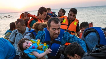 A man carries a girl in his arm as migrants arrive at a coast on a dinghy after crossing from Turkey in the southeastern island of Kos, Greece, during the sunrise early Thursday, Aug. 13, 2015 AP 
