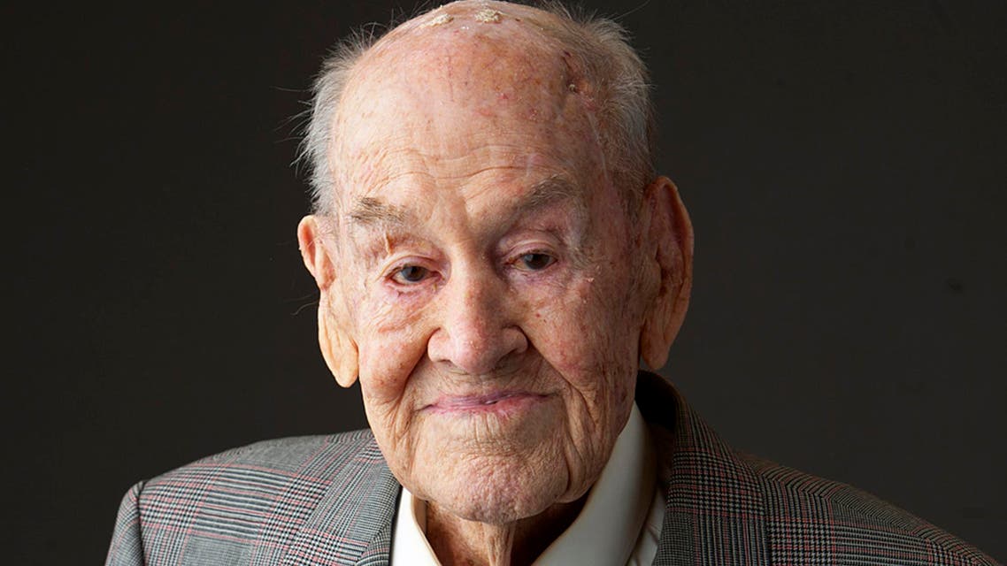 In this June 23, 2015 photo provided by Gordon Royle, his father Paul Royle poses for a photo holding a picture of himself in uniform during World War ll, in Perth, Australia. Paul Royle, an Australian pilot who took part in a mass breakout from a German prisoner of war camp during World War II that is remembered as The Great Escape, has died in his hometown of Perth, his son said Friday, Aug. 28, 2015. He was 101. (Garry Sarre/Gordon Royle via AP)