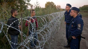  Syrian refugees and Hungarian police chat at the barbed wire fence at the border between Serbia and Hungary, in Roszke, Hungary Friday, Aug. 28, 2015. Hungary deployed police reinforcements to rein in an unrelenting flow of migrants across its porous border Thursday, but refugee activists said the effort appeared futile in a nation whose migrant camps are overloaded and barely delay their journeys west into the heart of the European Union. (AP Photo/Darko Bandic)