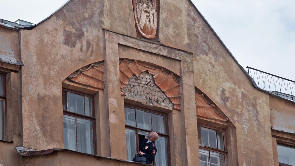 A police investigator looks up to at an empty spot where an old bas relief depicting the mythical demon Mephistopheles was removed in St. Petersburg, Russia, Friday, Aug. 28, 2015. (AP)