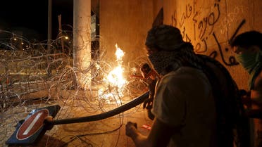 Protesters carry a broken street sign as they set trash on fire on barbed wire erected near the government palace in downtown Beirut, Lebanon August 29, 2015.