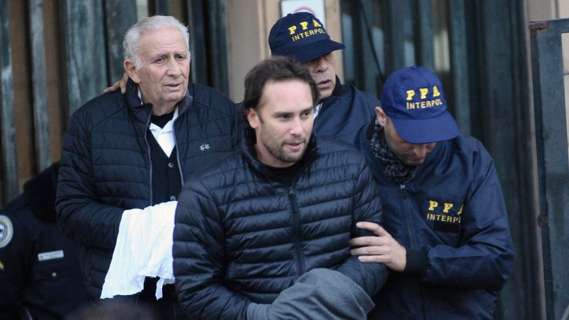 Hugo Jinkis, left, and his son Mariano, center, are escorted by police after they turned themselves in at a federal courthouse in Buenos Aires, Argentina, Thursday, June 18, 2015. The two Argentine businessmen are wanted in the United States in a FIFA bribery case. (AP Photo/Maxi Failla)