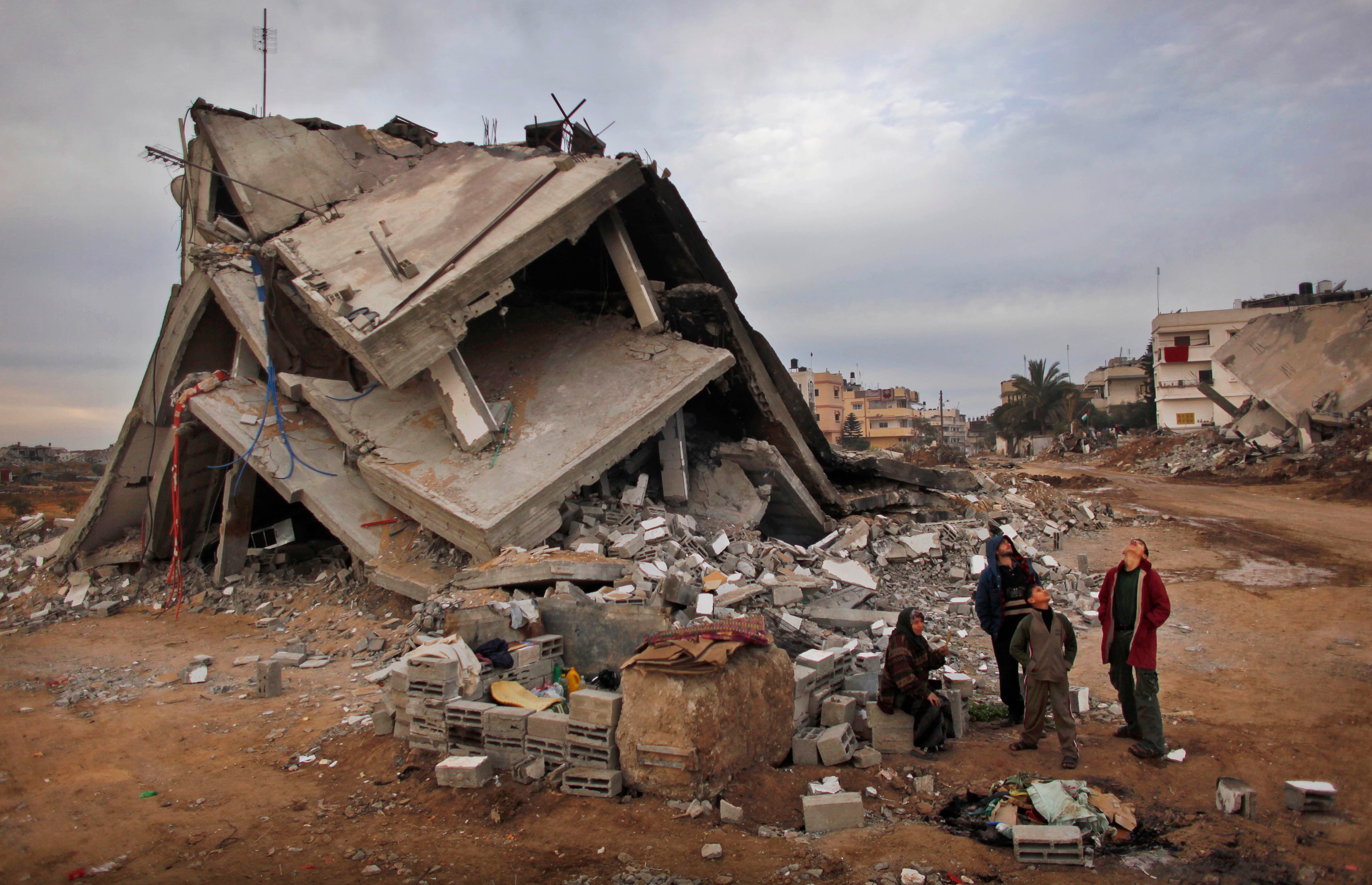Palestinians look up at an Israeli air force unmanned drone as they stand in the rubble of their destroyed house in the area of east Jebaliya, in the northern Gaza Strip, that was devastated in the last Israeli military offensive, Wednesday, Jan. 28, 2009. (Reuters)