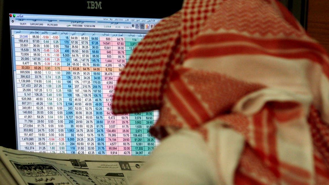A Saudi man reads a newspaper while keeping an eye on a screen displaying stock market figures, Wednesday, March 19, 2008, at al Jazeera Capital Bank in Riyadh, Saudi Arabia. The declining U.S. economy is affecting dollar-pegged Persian Gulf countries. (AP Photo/Hasan Jamali)