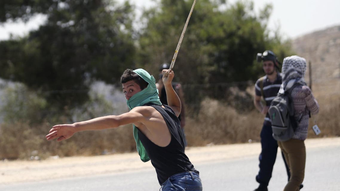 A Palestinian protester uses a sling to hurl a stone towards Israeli troops during clashes at a protest against Jewish settlements in the West Bank village of Nabi Saleh. (File: Reuters)
