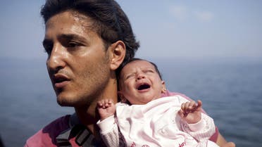 A Syrian refugee from Aleppo holds his one month old daughter moments after arriving on a dinghy on the Greek island of Lesbos. (Reuters)