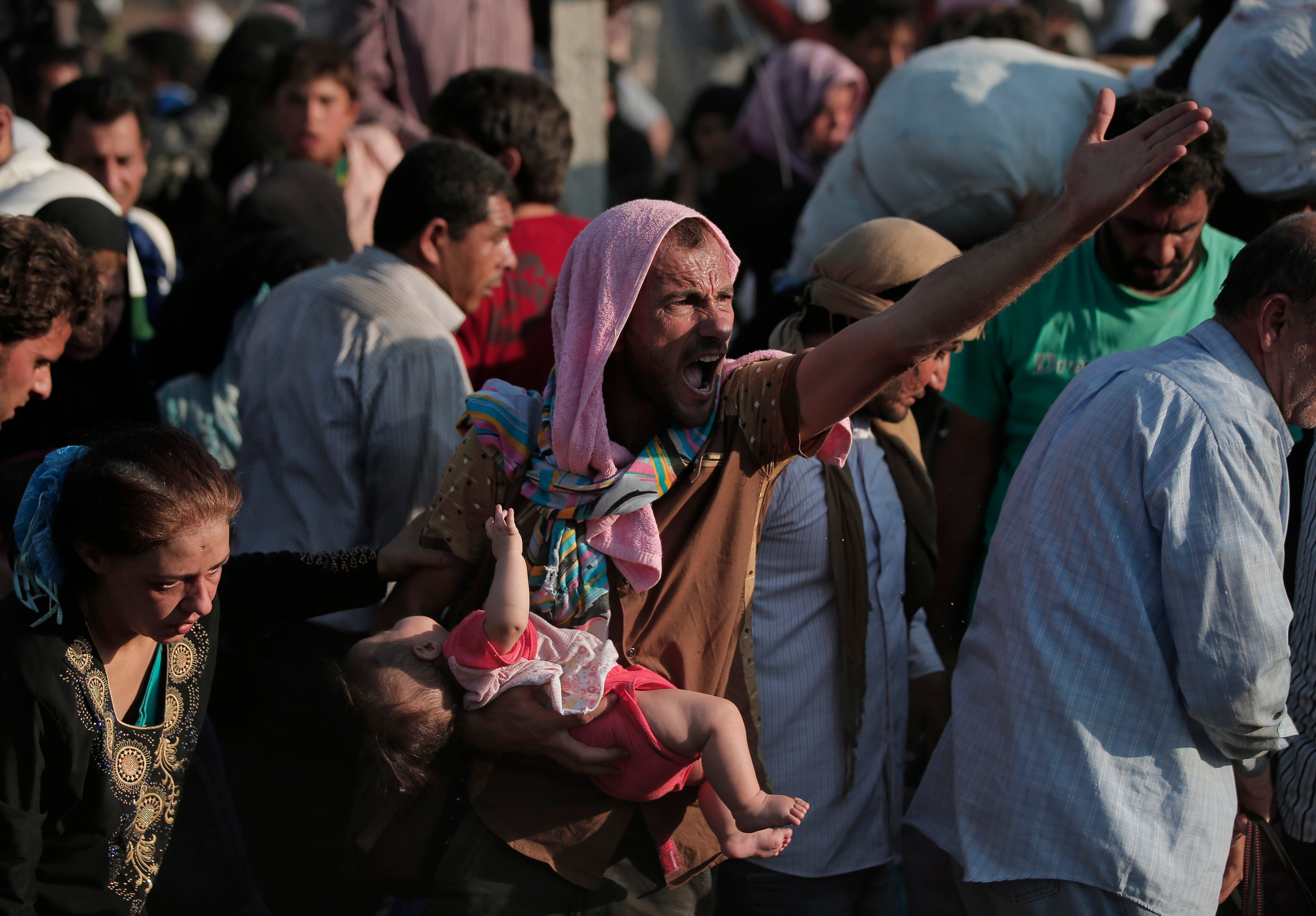 A Syrian refugee screams for help as he carries a baby after crossing over the broken border fence into Turkey from Syria in Akcakale, Sanliurfa province, southeastern Turkey, Sunday, June 14, 2015. AP