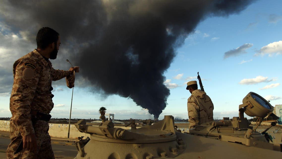 Libyan soldiers watch black smoke rising from Benghazi port during clashes with Islamist gunmen on December 23, 2014. (AFP)