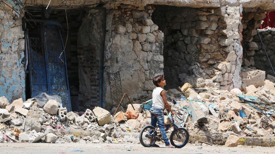 A boy with his bicycle stands near buildings destroyed during fighting between tribal fighters and Shiite rebels known as Houthis at a street in Taiz, Yemen, Sunday, Aug. 23, 2015.  AP 