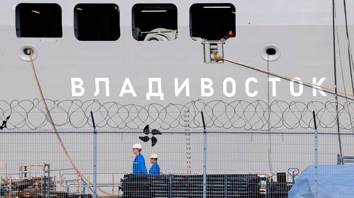 In this Sept.5, 2014 file photo, workers walk past the the Vladivostok warship on the port of Saint-Nazaire, western France. France will refund 950 million euro ($1 billion) to Russia for the cancellation of the sale of two Mistral-class warships, but avoid paying penalties. (AP Photo/David Vincent, File)
