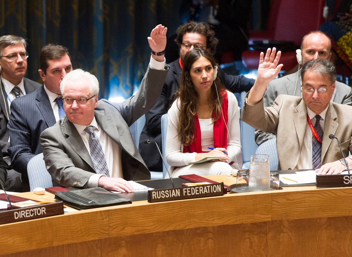 Vitaly Churkin , (L), Permanent Representative of the Russian Federation to the United Nations casts his vote as Security Council votes to adopt a resolution creating a joint investigative mechanism to identify individuals or entities responsible for the use of chemical weapons in Syria.