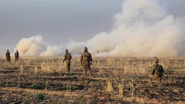Kurdish Peshmerga fighters walk with their weapons as smoke rises from a site of clashes south of Daquq, north of Baghdad. (File: Reuters)