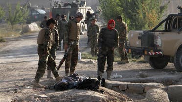Afghan National Army (ANA) soldiers stand over the body of a Taliban insurgent outside a prison in Ghazni, Afghanistan, September 14, 2015.