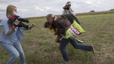 A migrant runs with a child before tripping on TV camerawoman Petra Laszlo (L) and falling as he tries to escape from a collection point in Roszke village, Hungary, September 8, 2015. Laszlo, a camerawoman for a private television channel in Hungary, was fired late on Tuesday after videos of her kicking and tripping up migrants fleeing police, including a man carrying a child, spread in the media and on the internet. REUTERS/Marko Djurica