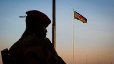 A South-Sudanese government soldier stands guard as a South Sudanese flag flies in the background AP