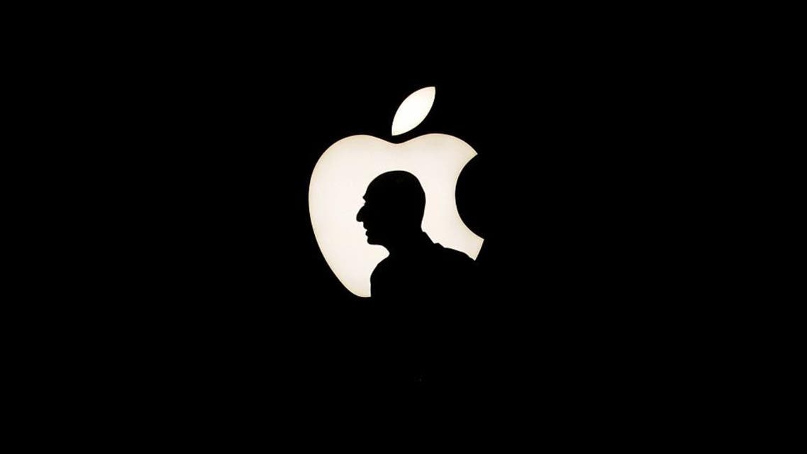 A man walks past a backlit Apple logo during an Apple media event in San Francisco. (Reuters)