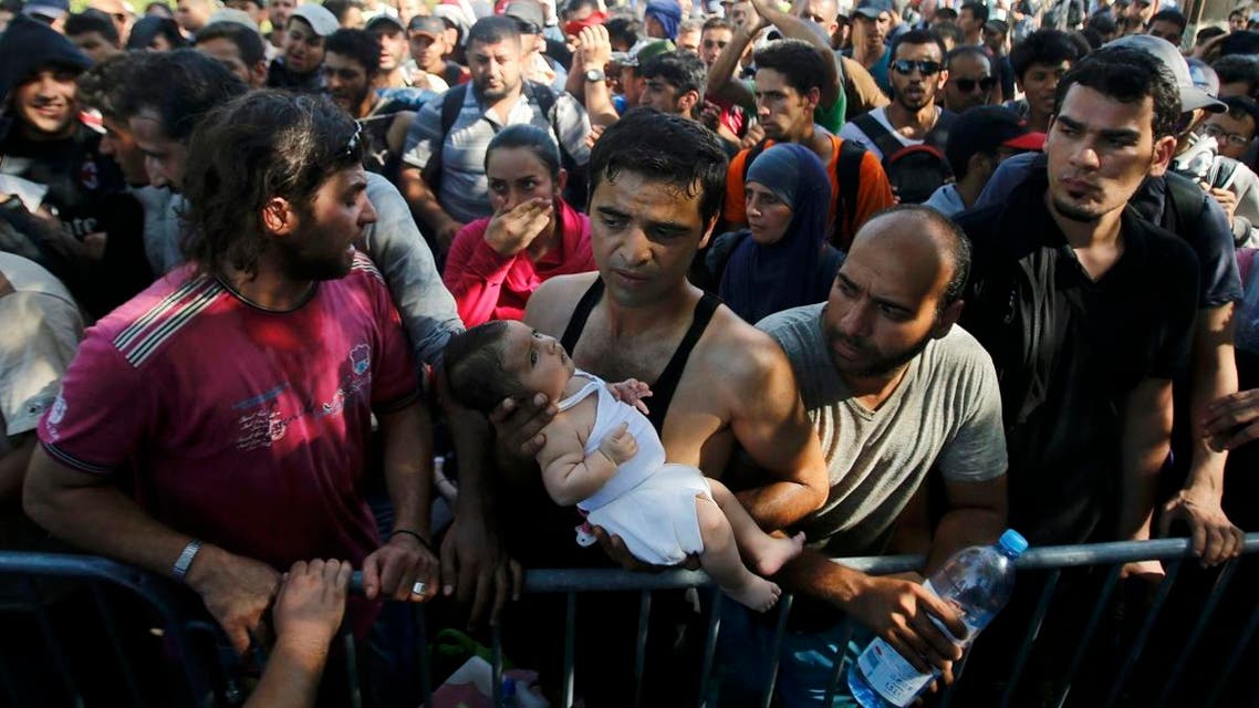 A migrant holds a baby as he waits to board a bus in Tovarnik, Croatia, September 17, 2015. reuters