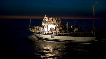 A spotlight from an Italian Coast boat shines on a boat loaded with migrants spotted at sea off the Sicilian island of Lampedusa, Italy, early Monday, March 7, 2011.