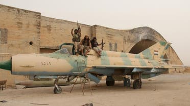 Members of Al-Qaeda's Syrian affiliate and its allies sit on a Syrian army MiG-21 fighter jet after they seized the Abu Duhur military airport on September 9, 2015 (AFP Photo/Omar Haj Kadour) 