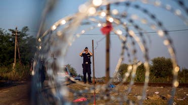 A Hungarian police officer looks through binoculars as he checks the border for refugees entering the country illegally next to the town of Röszke, Hungary. (AP Photo)