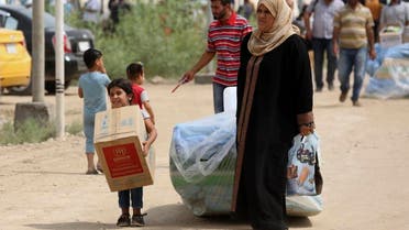 Iraqi family members internally displaced carry humanitarian aid being distributed at a refugee camp in Baghdad's western neighborhood of Ghazaliyah, Iraq, Wednesday, Sept. 16, 2015. The camp accommodating people from Anbar province's Ramadi and around received humanitarian aid Wednesday. (AP Photo/Hadi Mizban)