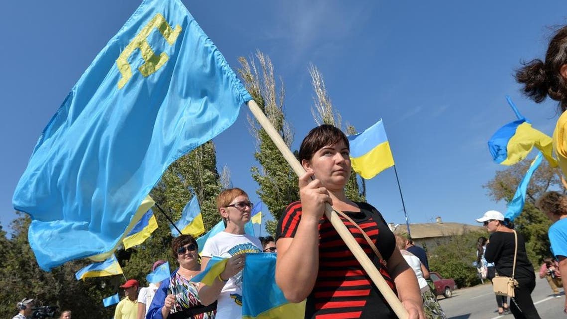 Activists hold Ukrainian and Crimean Tatar flags as they block the road at the checkpoint between Ukraine and Crimea, in Chongar, on September 20, 2015. AP