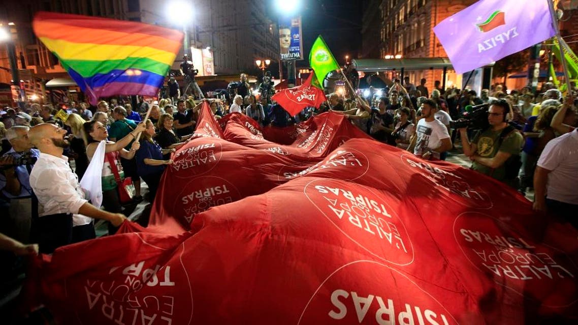 Supporters of the left-wing Syriza party react after the election results at the party’s main electoral center in Athens, Sunday, Sept. 20, 2015. The official projection of final results in Greece's early election shows the left-wing Syriza party of former Prime Minister Alexis Tsipras winning with 35.5 percent, but falling short of enough parliamentary seats to form a government on its own. The giant flag reads in Italian "The other Europe with Tsipras. (AP Photo/Lefteris Pitarakis)