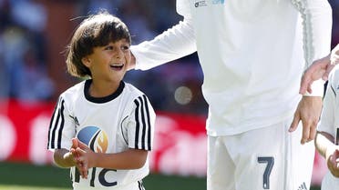 Zaid, 7, son of Osama Abdul Mohsen, a Syrian refugee who was filmed being tripped by a camerawoman as he fled police in Hungary with him, smiles as he stands next to Real Madrid's Cristiano Ronaldo before the Spanish first division soccer match against Granada at Santiago Bernabeu stadium in Madrid, Spain, September 19, 2015. REUTERS/Sergio Perez