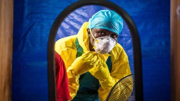 In this Oct. 16, 2014, file photo, a healthcare worker dons protective gear before entering an Ebola treatment center in Freetown, Sierra Leone. 
