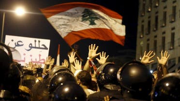 Protesters raise their hands facing riot police during a protest against perceived government failures, including a rubbish disposal crisis, in downtown Beirut. (Reuters)