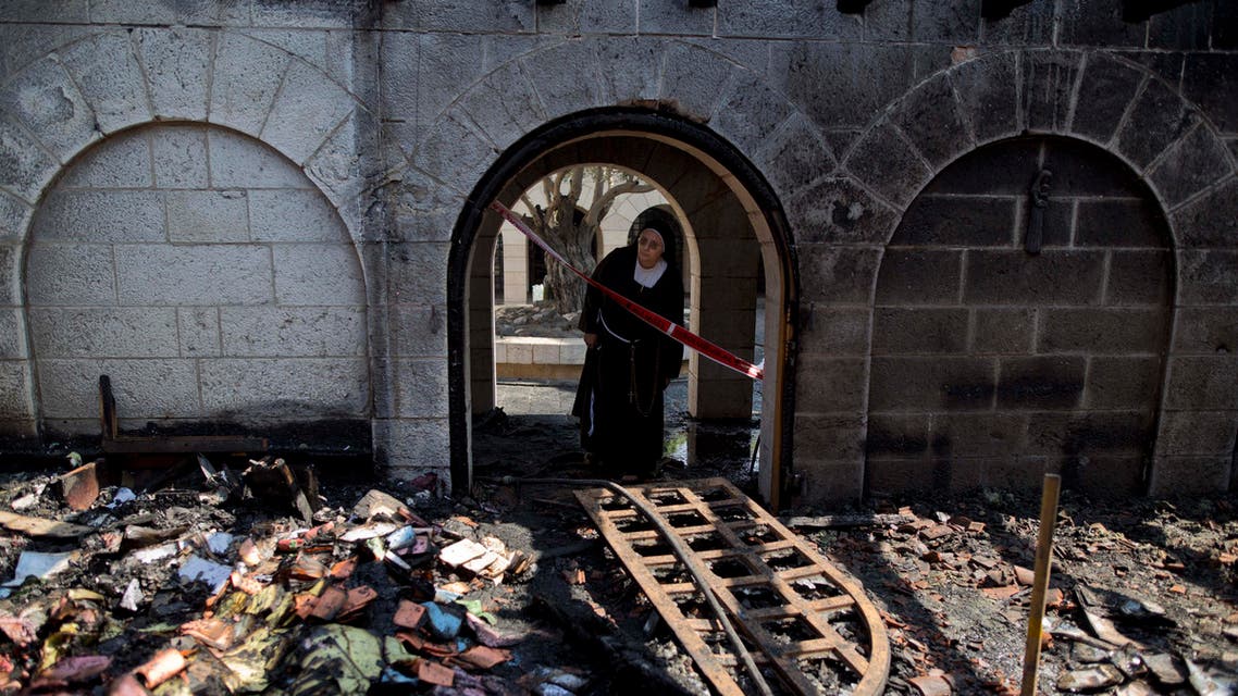  FILE - In this Thursday, June 18, 2015 file photo, a nun looks at damage to the Church of the Multiplication of the Loaves and Fish after an arson attack overnight on the shore of the Sea of Galilee in Tabgha, northern Israel. Israeli police said on Sunday, July 12, 2015, that they have arrested a number of suspects, without elaborating on their identity, in last month's arson attack on the Catholic church. The fire is believed to be an attack by Jewish extremists on one of the most popular stops for Christian pilgrims visiting the Holy Land. (AP Photo/Ariel Schalit, File)