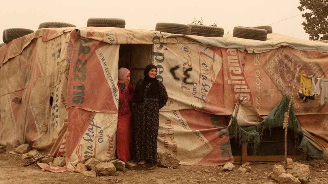 Syrian refugees stand outside their tents during a sandstorm in a refugee camp in the town of Bar Elias, in Lebanon’s Bekaa Valley, on Sept. 8, 2015. (AP Photo/Bilal Hussein)