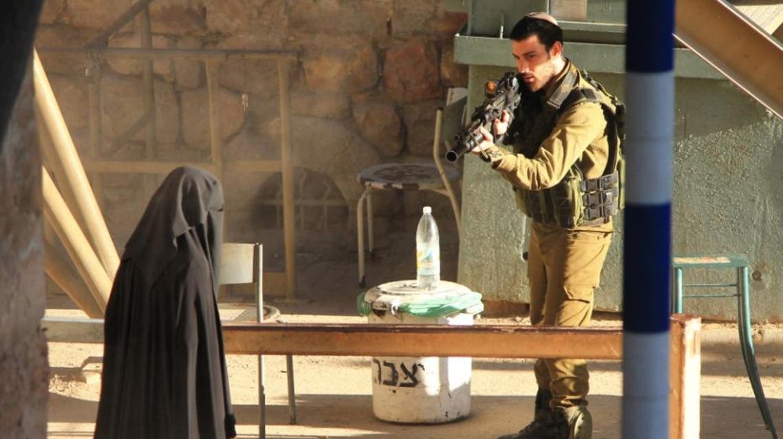 In this photo made available on Tuesday, Sept. 22, 2015 by the Youth Against Settlements, a Palestinian activist network the opposes Jewish settlements in the West Bank, an Israeli soldier aims at a Palestinian woman at a checkpoint in the West Bank city of Hebron. 