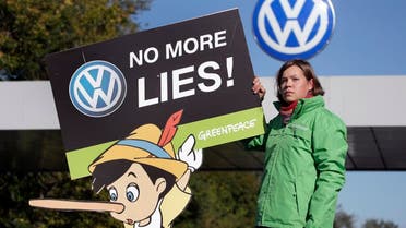 An activist of the environmental protection organization 'Greenpeace' holds a protest poster in front of a factory gate of the German car manufacturer Volkswagen in Wolfsburg, Germany, Friday, Sept. 25, 2015, where the supervisory board meet to discuss who to name as CEO after Martin Winterkorn quit the job this week over an emissions-rigging scandal that's rocking the world's top-selling automaker. (AP Photo/Michael Sohn)