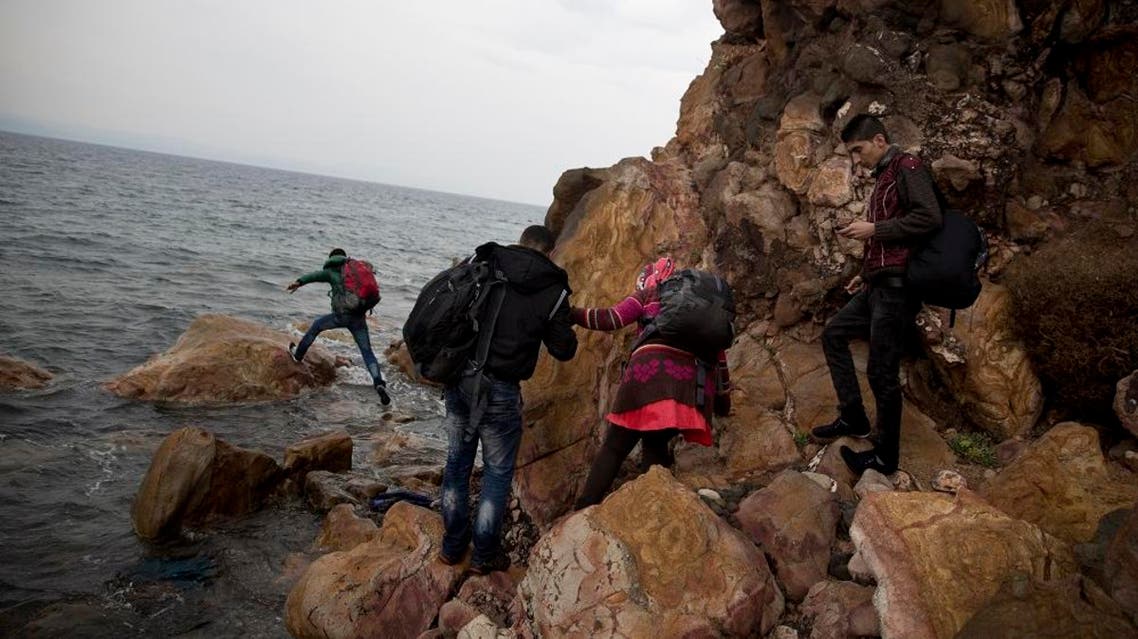 Syrian refugees who arrived on the shores of the Greek island of Lesbos after crossing the Aegean Sea from Turkey on a inflatable dinghy, clamber over rocks on Tuesday, Sept. 22, 2015.