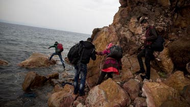 Syrian refugees who arrived on the shores of the Greek island of Lesbos after crossing the Aegean Sea from Turkey on a inflatable dinghy, clamber over rocks on Tuesday, Sept. 22, 2015. 